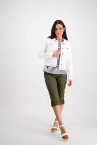 A woman wears the Vassalli Ratio Jacket in white denim over a black-and-white striped shirt, olive green capri pants, and white sandals, standing against a plain white background with a soft smile.