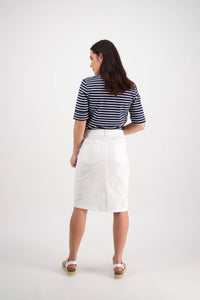 A woman faces away, wearing a navy and white striped shirt, the Vassalli Poppy Poplin Skirt in white, and white sandals. Set against a light background, this look is perfect for effortless everyday style.