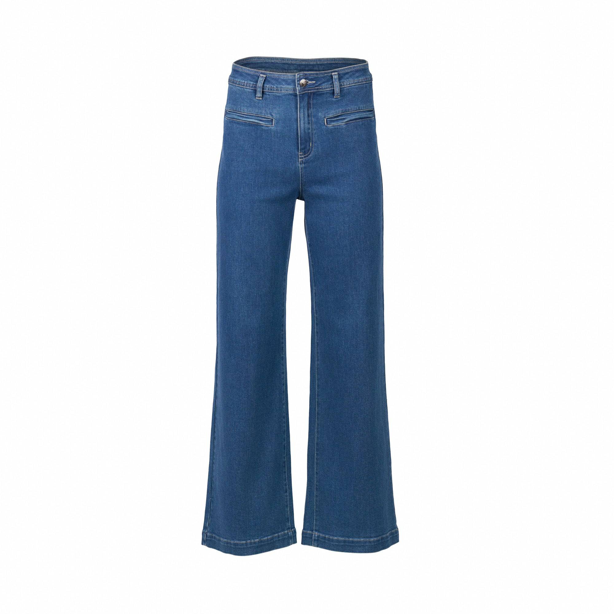 The Vassalli Peace Jean in Blue Wash is a high-waisted, wide leg jean with flared legs, front zipper pockets, and stretch fabric, shown on a plain white background.