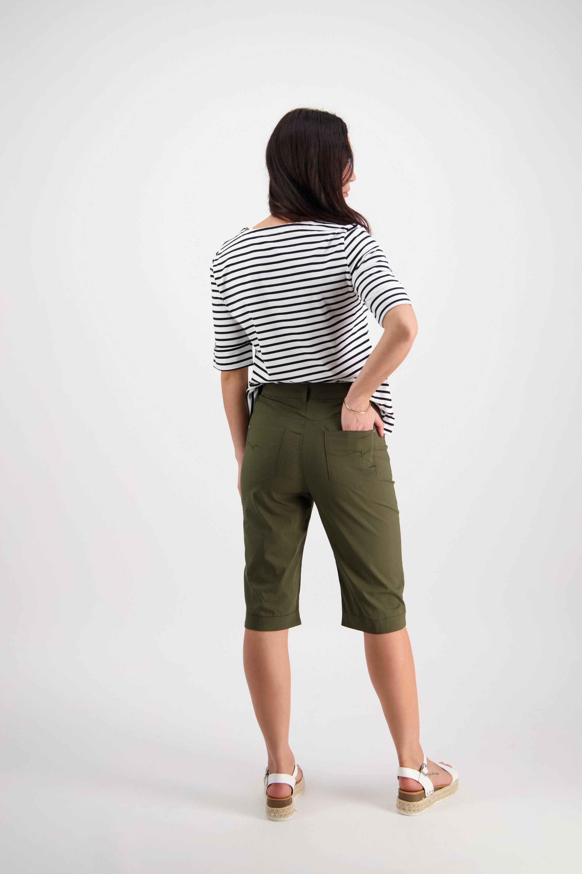 A woman faces away, wearing a black and white striped shirt, Vassalli’s Custom Poplin Short in khaki, and white sandals against a plain light background.