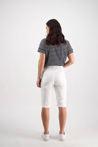 A person with shoulder-length dark hair stands facing away, wearing the Vassalli Custom Poplin Short in White, styled with a black and white striped shirt and white sneakers against a plain light background.