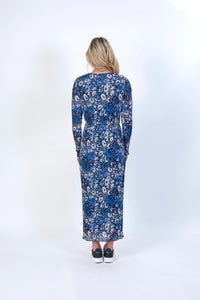 Woman wearing long-sleeve blue floral maxi dress with sneakers, back view