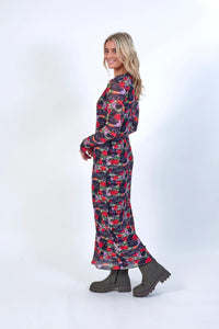 Woman wearing a long sleeve floral print dress and chunky ankle boots, side view