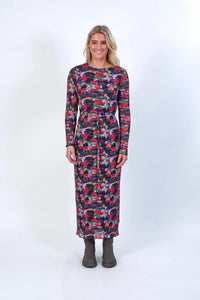 Woman wearing a long-sleeve abstract floral print dress with tie waist and boots, studio background