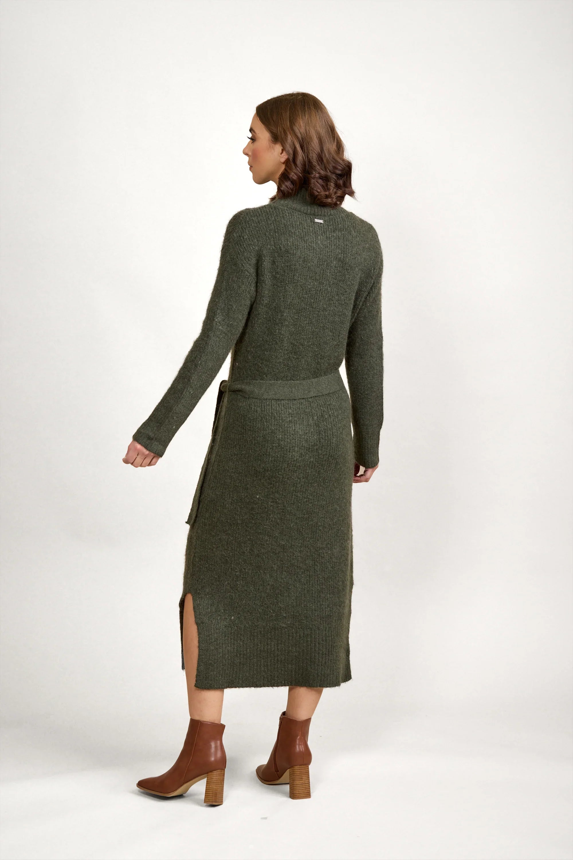 Woman in olive green knit midi dress with belt and side slit, brown ankle boots