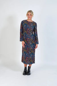 Woman wearing a long sleeve, multicolored patterned midi dress with black ankle boots