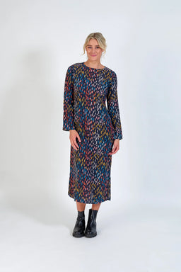 Woman wearing a long sleeve, multicolored patterned midi dress with black ankle boots