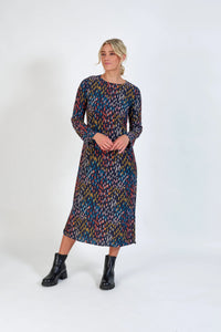 Woman wearing a long-sleeve, midi dress with colorful abstract pattern and black boots