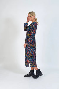 Woman wearing a long-sleeve, multicolour patterned midi dress with black ankle boots, side pose