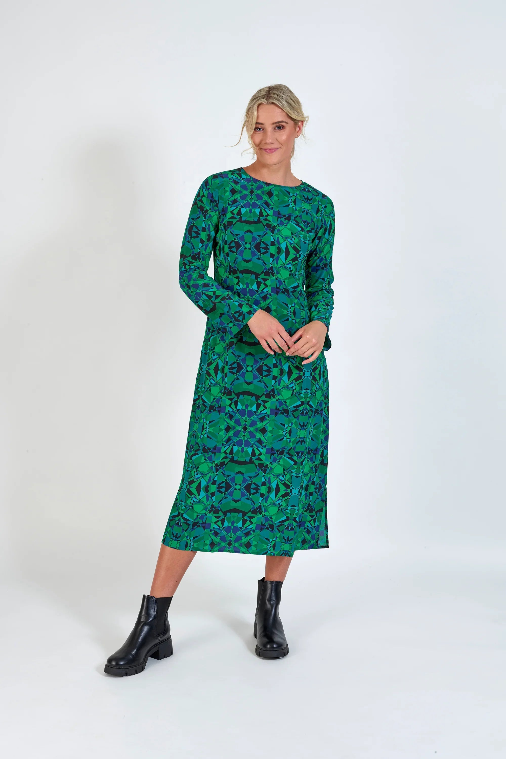 Woman wearing long sleeve green geometric print midi dress with black ankle boots