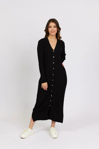 Woman wearing a long black ribbed button-down knit dress with white sneakers