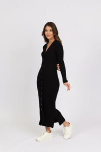 Woman wearing a black ribbed button-front knit dress with long sleeves and white sneakers