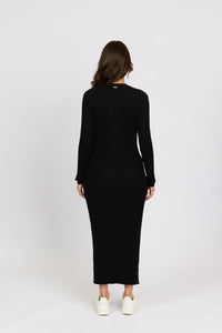 Back view of woman in black ribbed knit long-sleeve midi dress with white sneakers