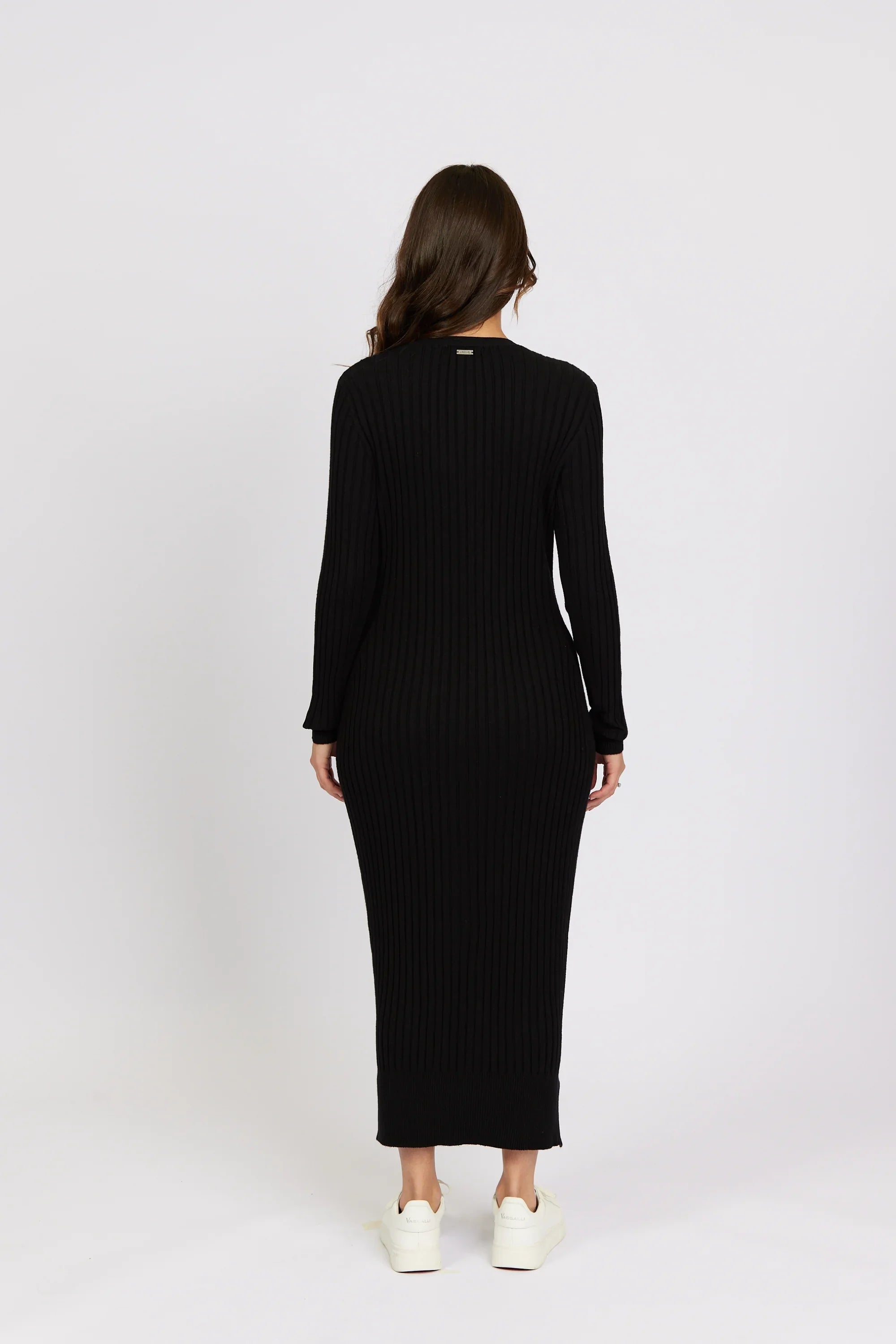 Back view of woman in black ribbed knit long-sleeve midi dress with white sneakers