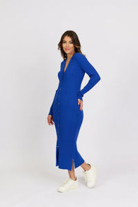 Woman wearing a long electric blue ribbed knit dress with buttons and white sneakers