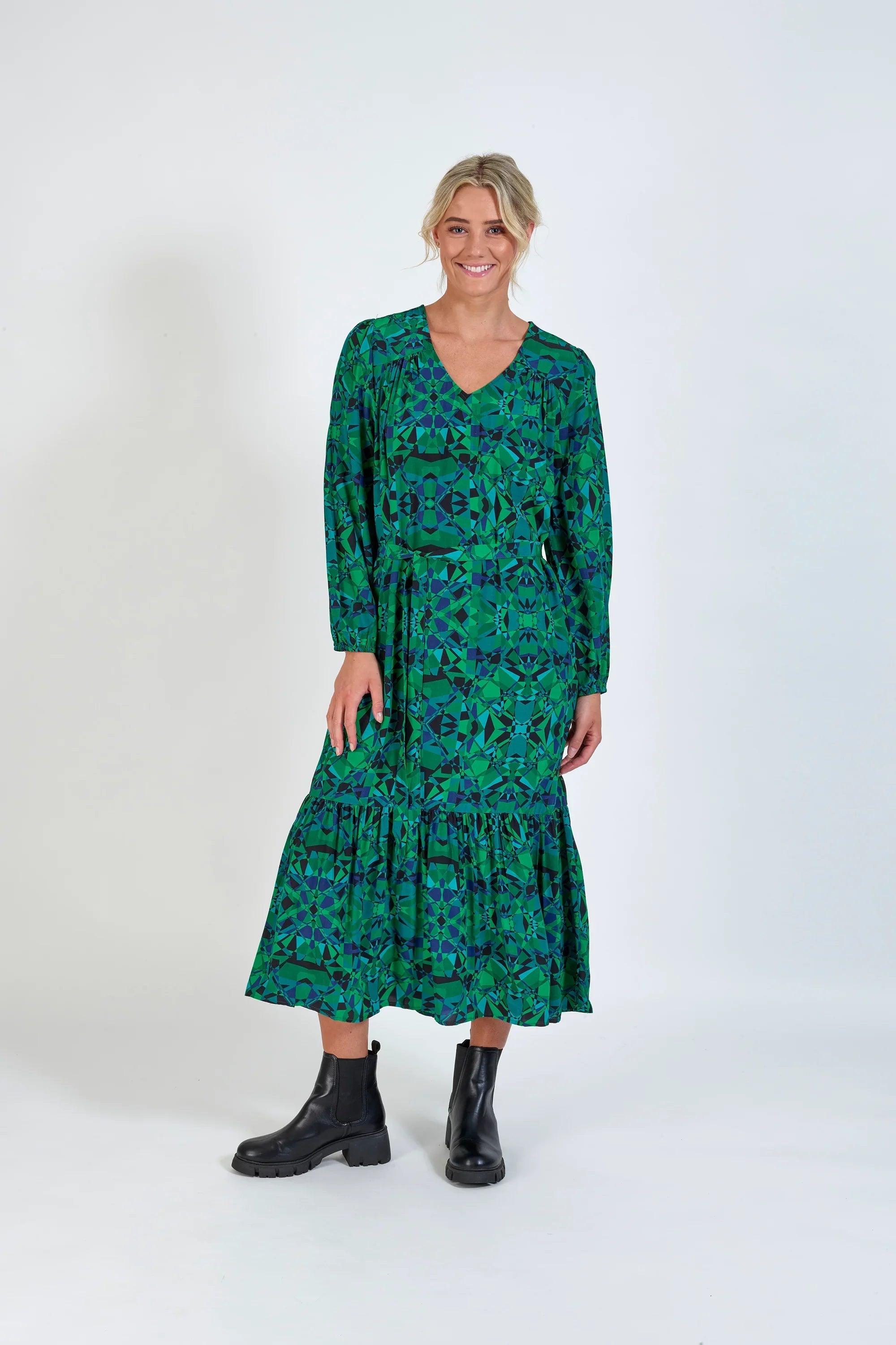 Woman wearing a long-sleeved green geometric print midi dress with black boots