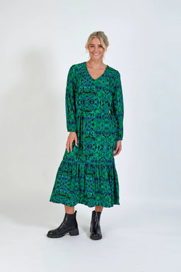 Woman wearing a long-sleeved green geometric print midi dress with black boots