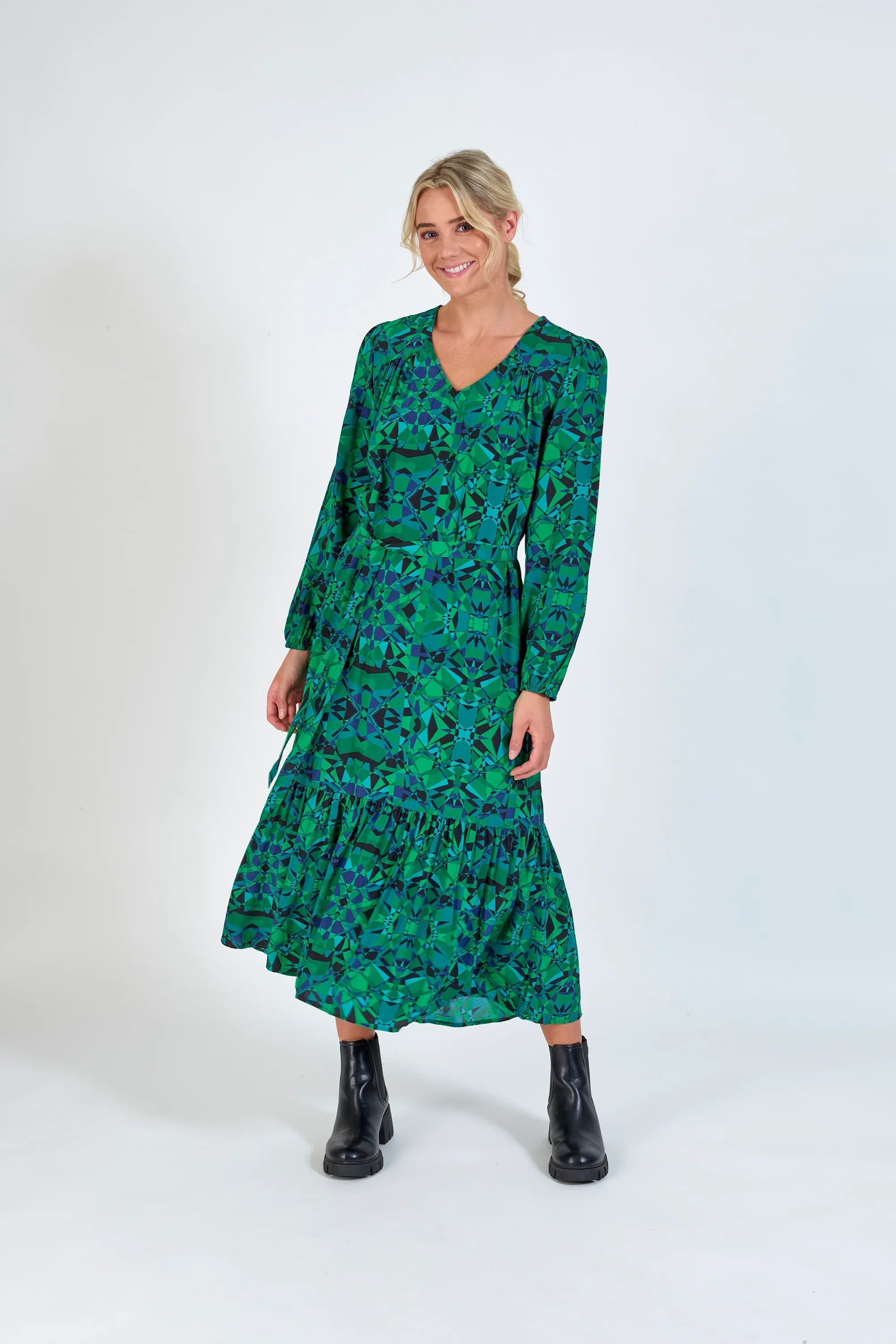 Woman wearing green geometric print long-sleeve midi dress with black ankle boots