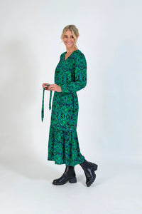 Woman wearing a green geometric print midi dress with long sleeves and black boots
