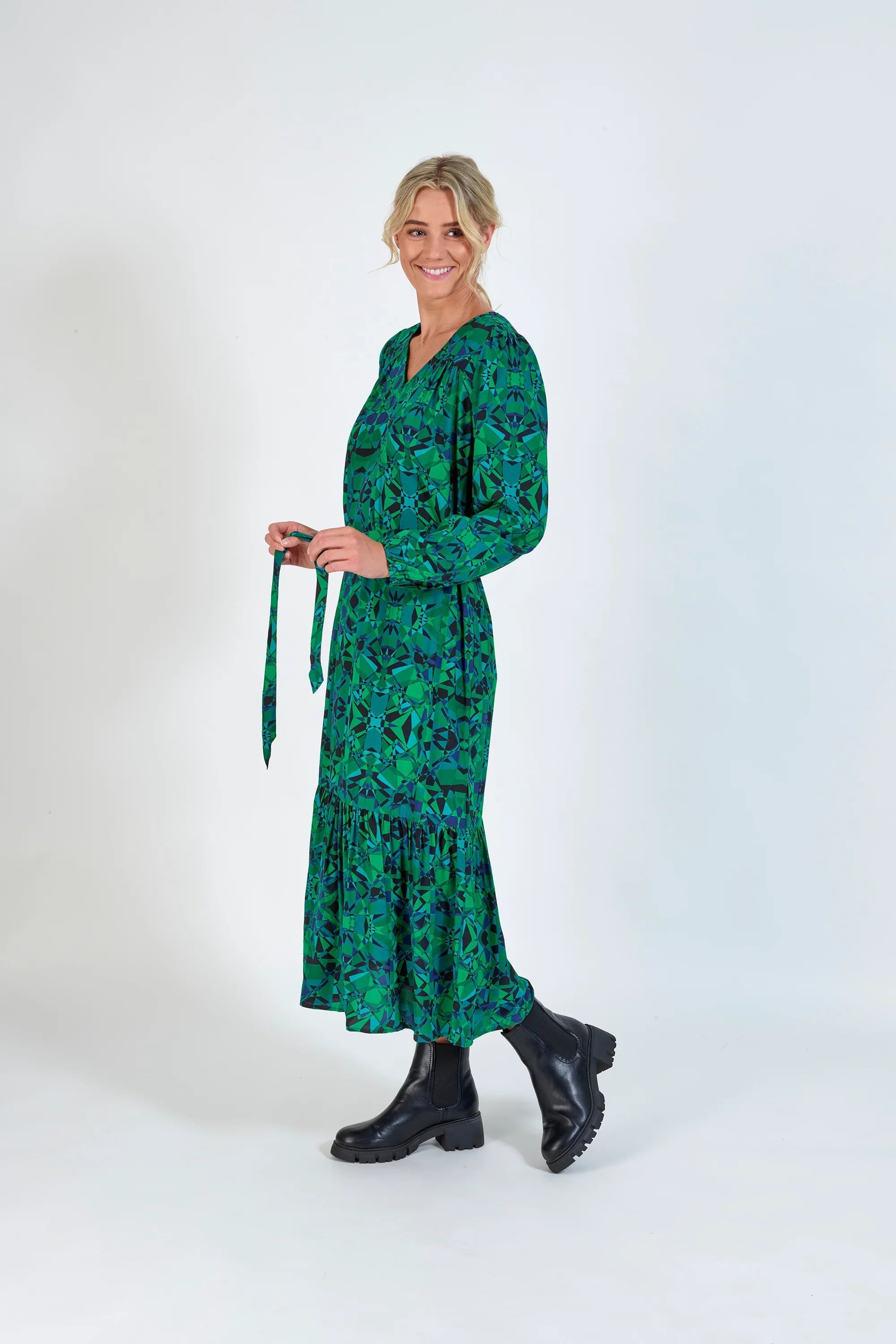 Woman wearing a green geometric print midi dress with long sleeves and black boots