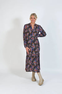 Woman in long-sleeve floral print midi dress with neutral boots, standing against white background
