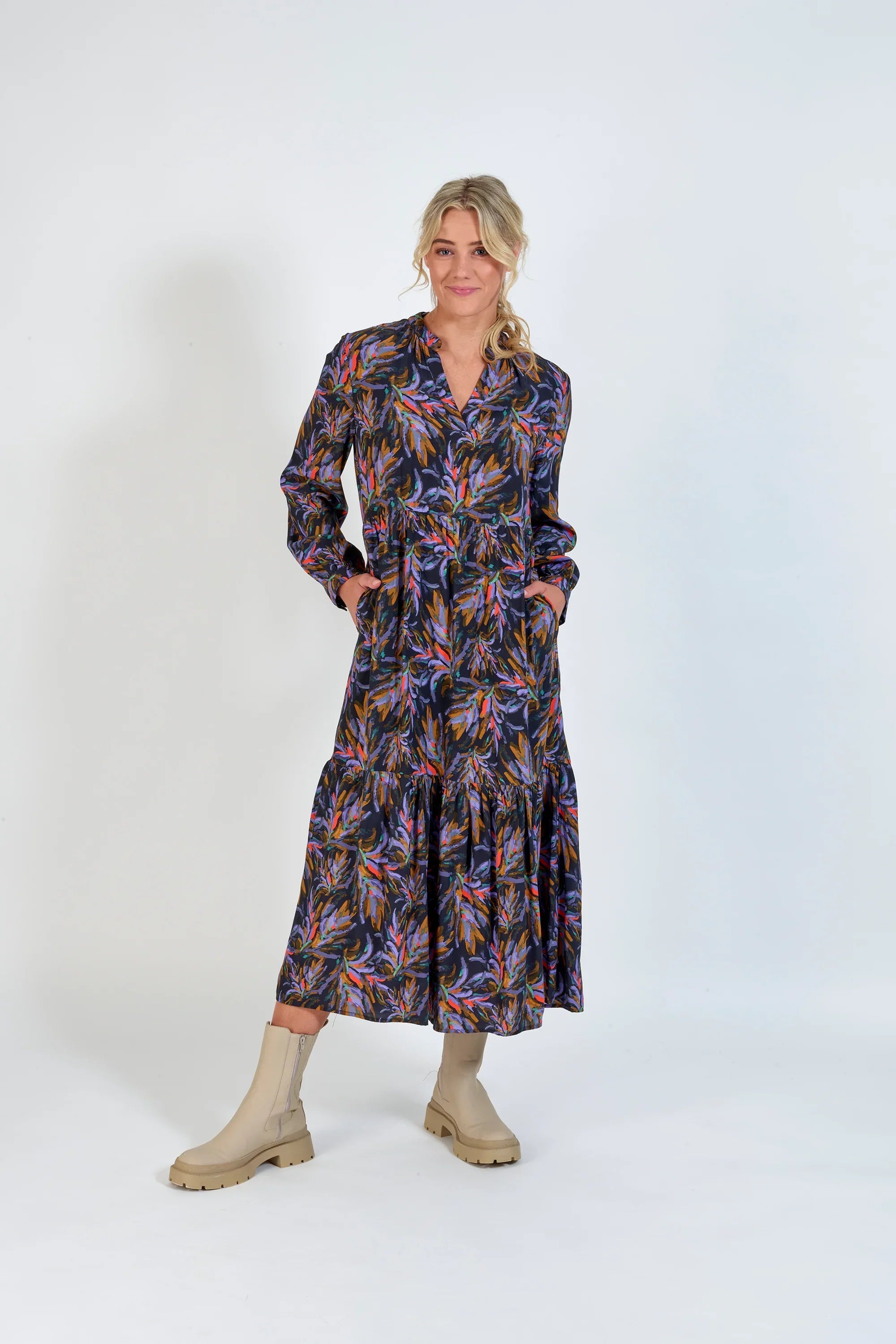 Woman wearing long-sleeve floral print midi dress with cream ankle boots, studio background