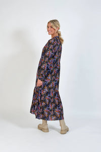 Woman wearing a long-sleeve, abstract floral print maxi dress with beige boots