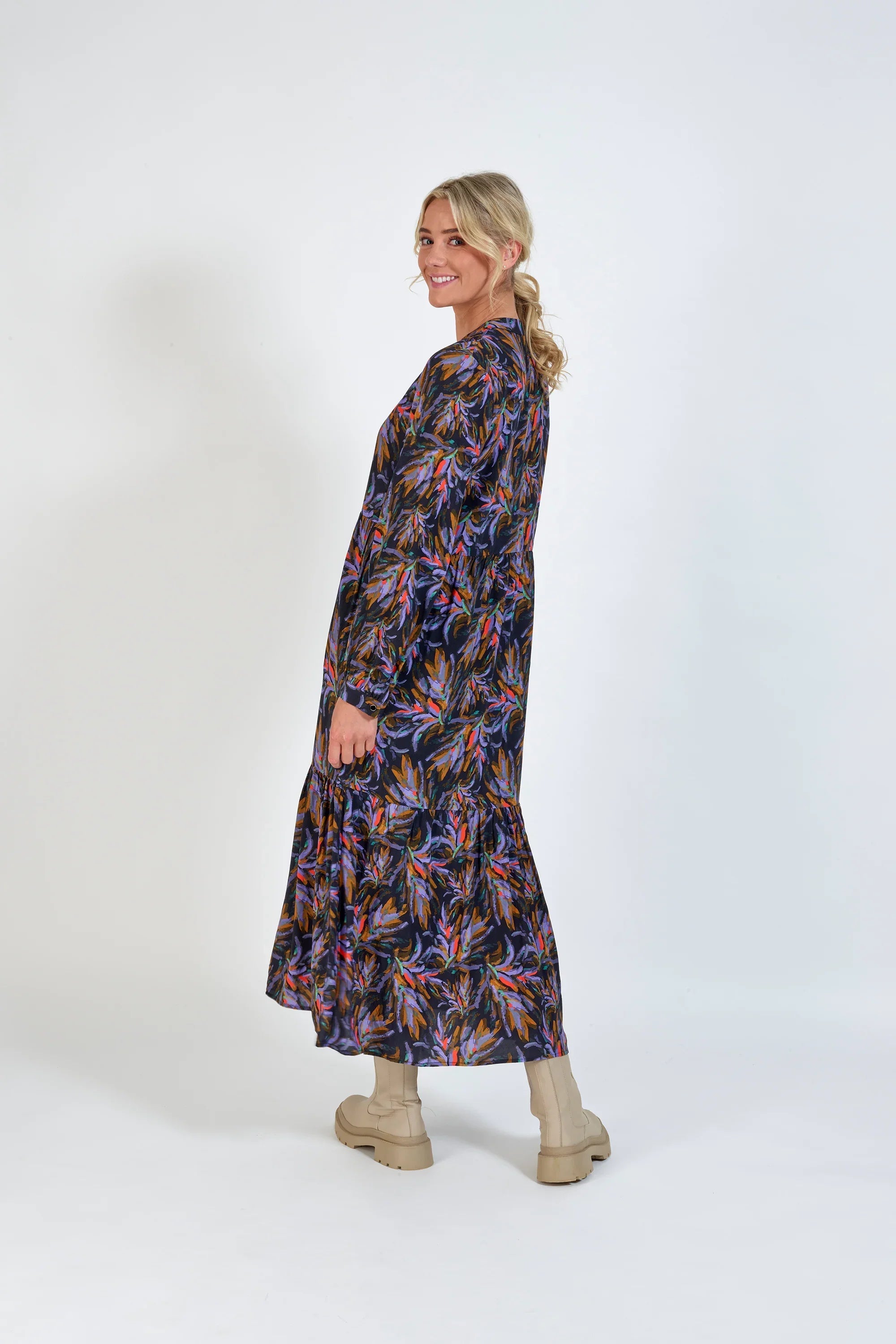 Woman wearing a long-sleeve, abstract floral print maxi dress with beige boots