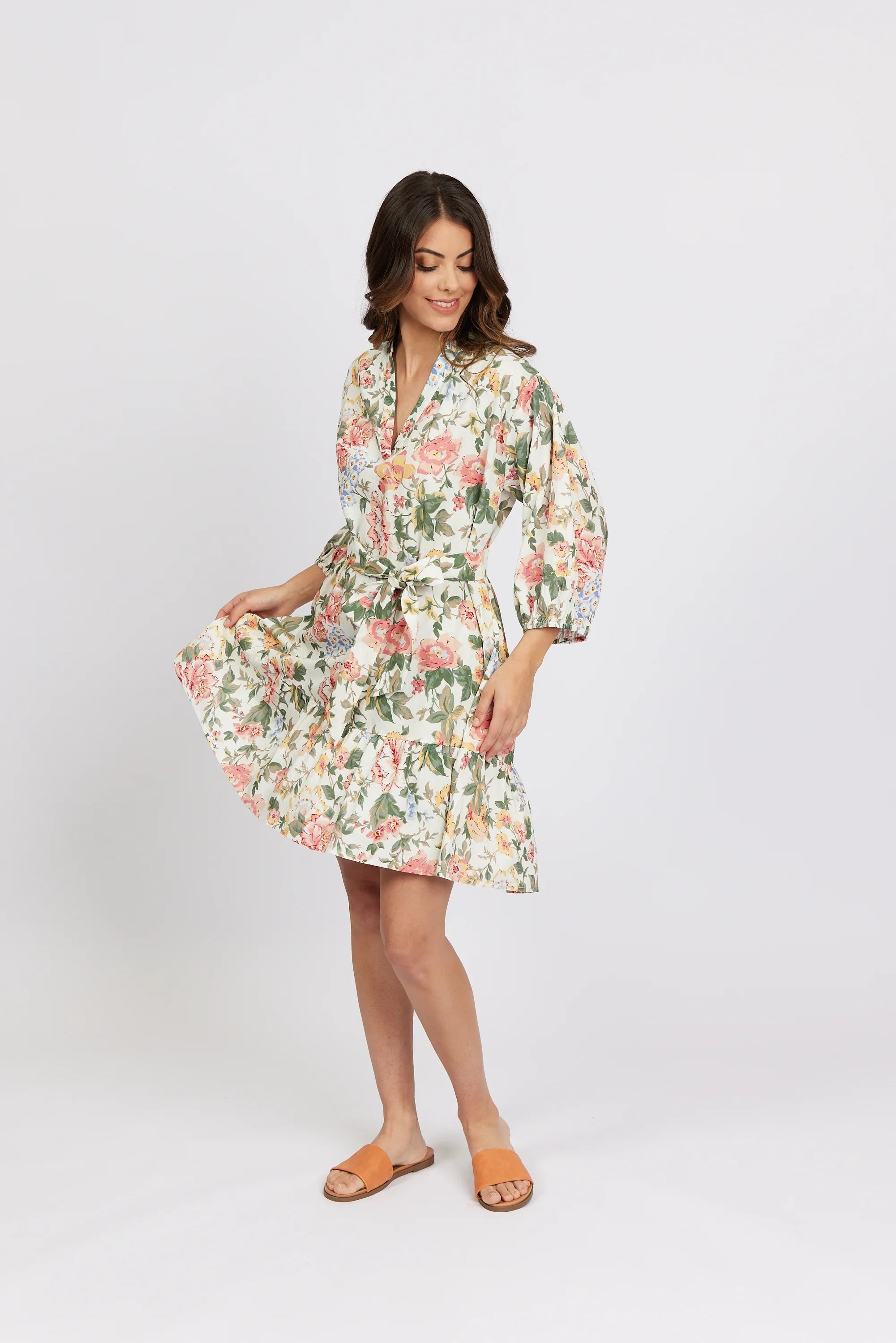 Woman wearing a knee-length floral print dress with long sleeves and a waist tie