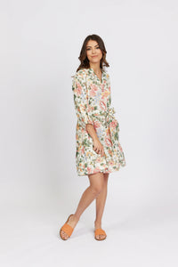 Woman in a knee-length floral belted dress with three-quarter sleeves, posing indoors