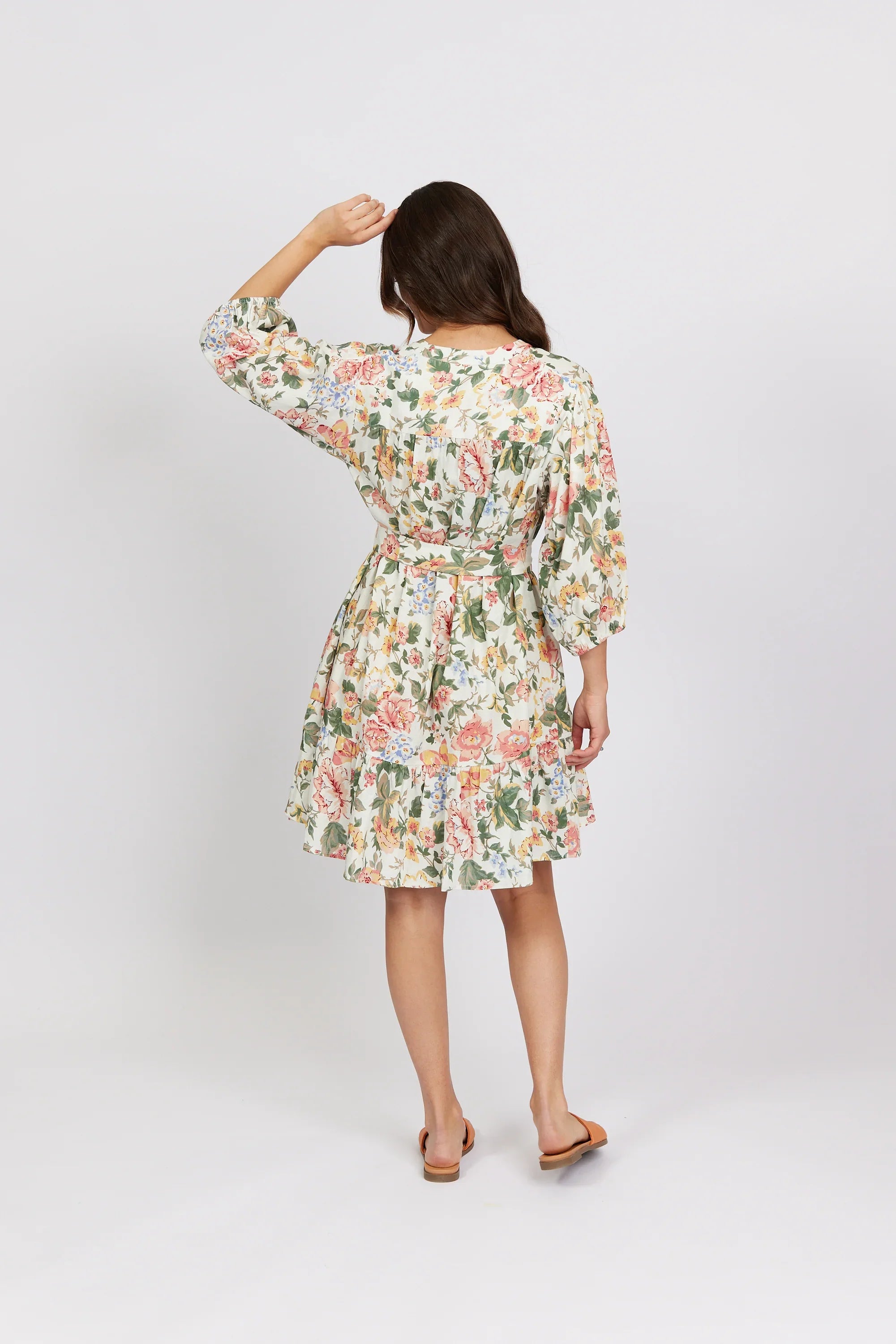 Woman in a floral print belted dress with puff sleeves, standing against a plain background
