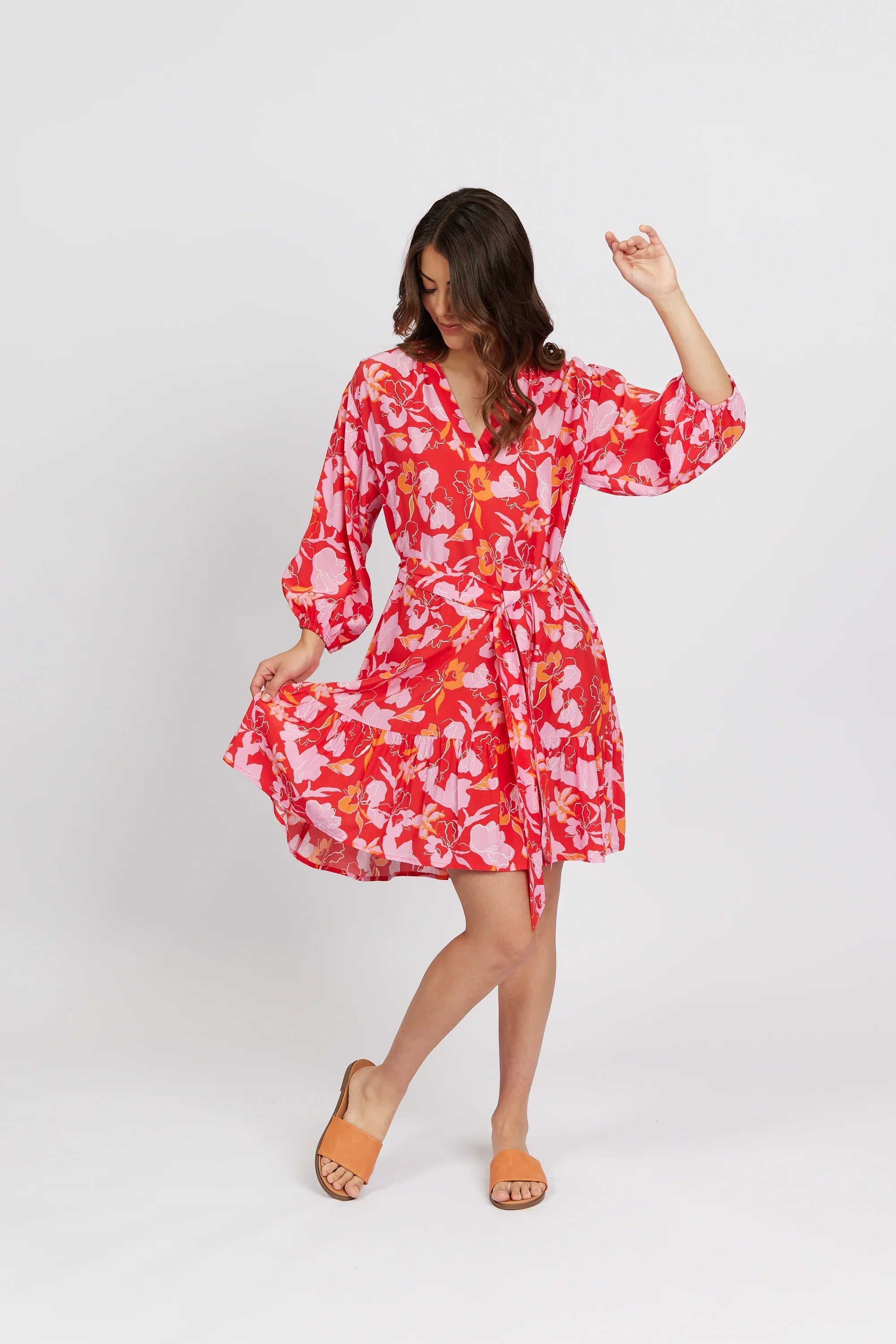 Woman wearing a vibrant floral print knee-length dress with long sleeves and tie waist
