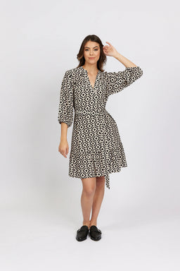 Woman wearing a geometric print wrap dress with three-quarter sleeves in a studio setting.