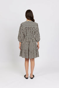 Back view of woman wearing black and white geometric print knee-length dress with puff sleeves