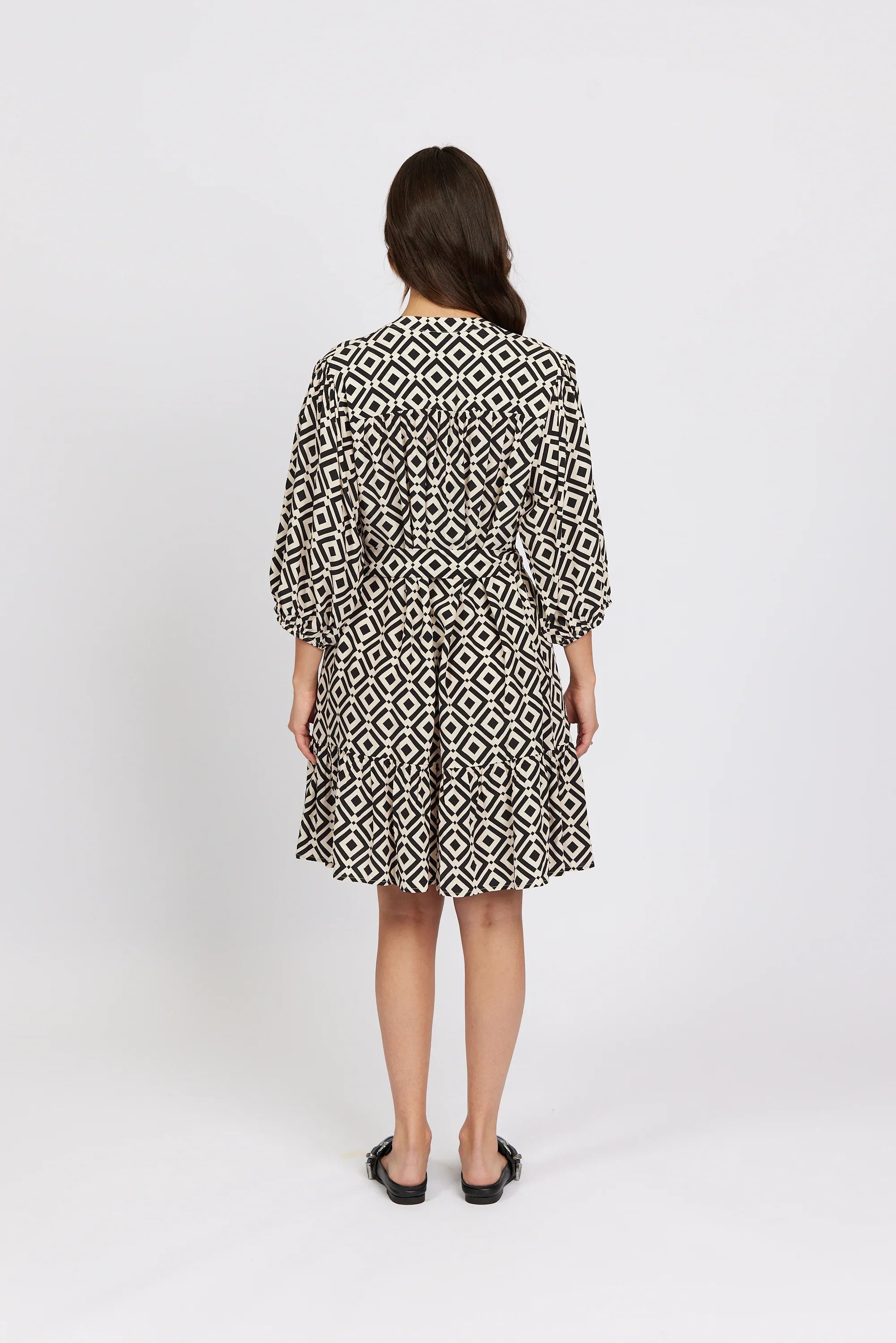 Back view of woman wearing black and white geometric print knee-length dress with puff sleeves