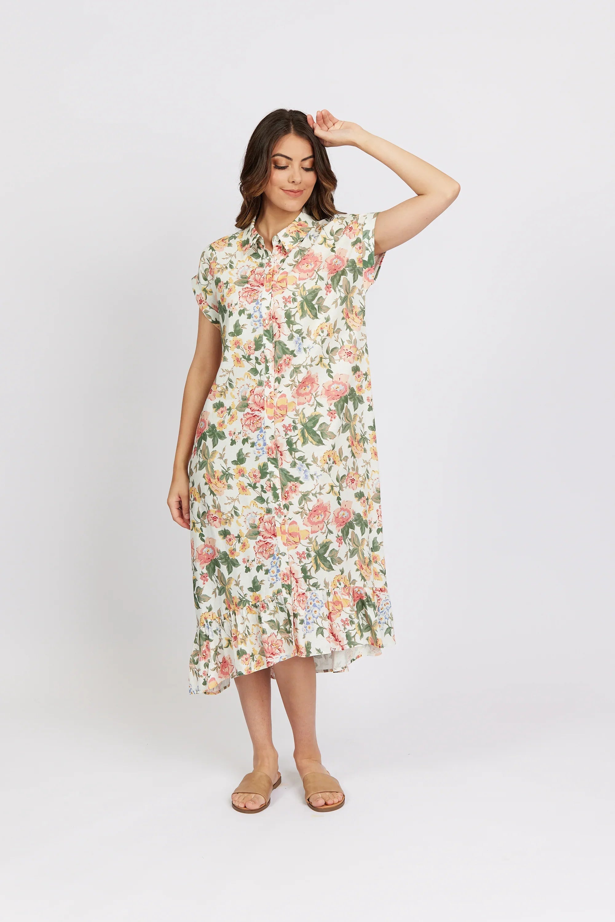 Woman wearing floral short-sleeve midi dress with ruffled hem, standing against white background