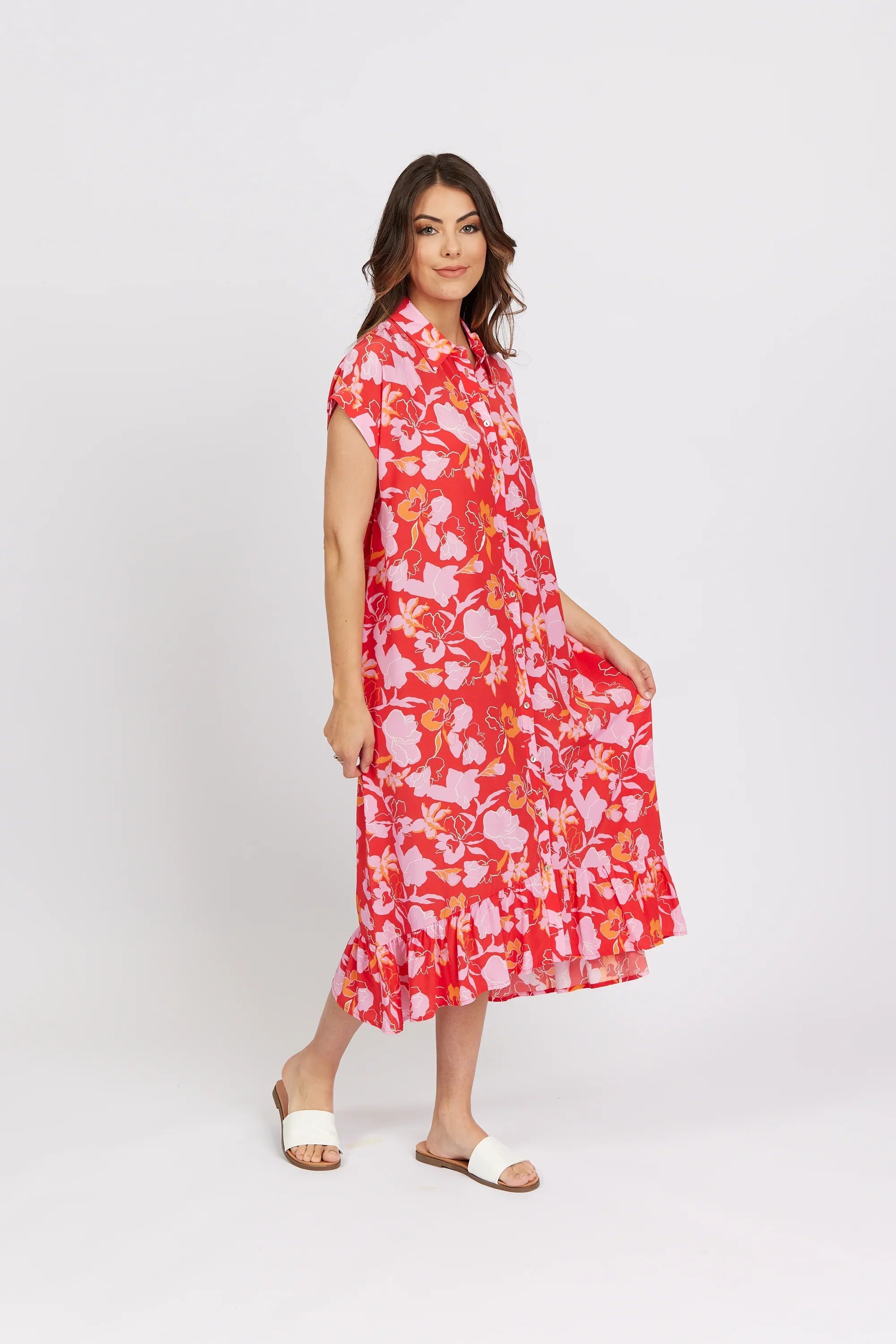 Woman wearing a red floral midi dress with short sleeves, ruffle hem and white slide sandals