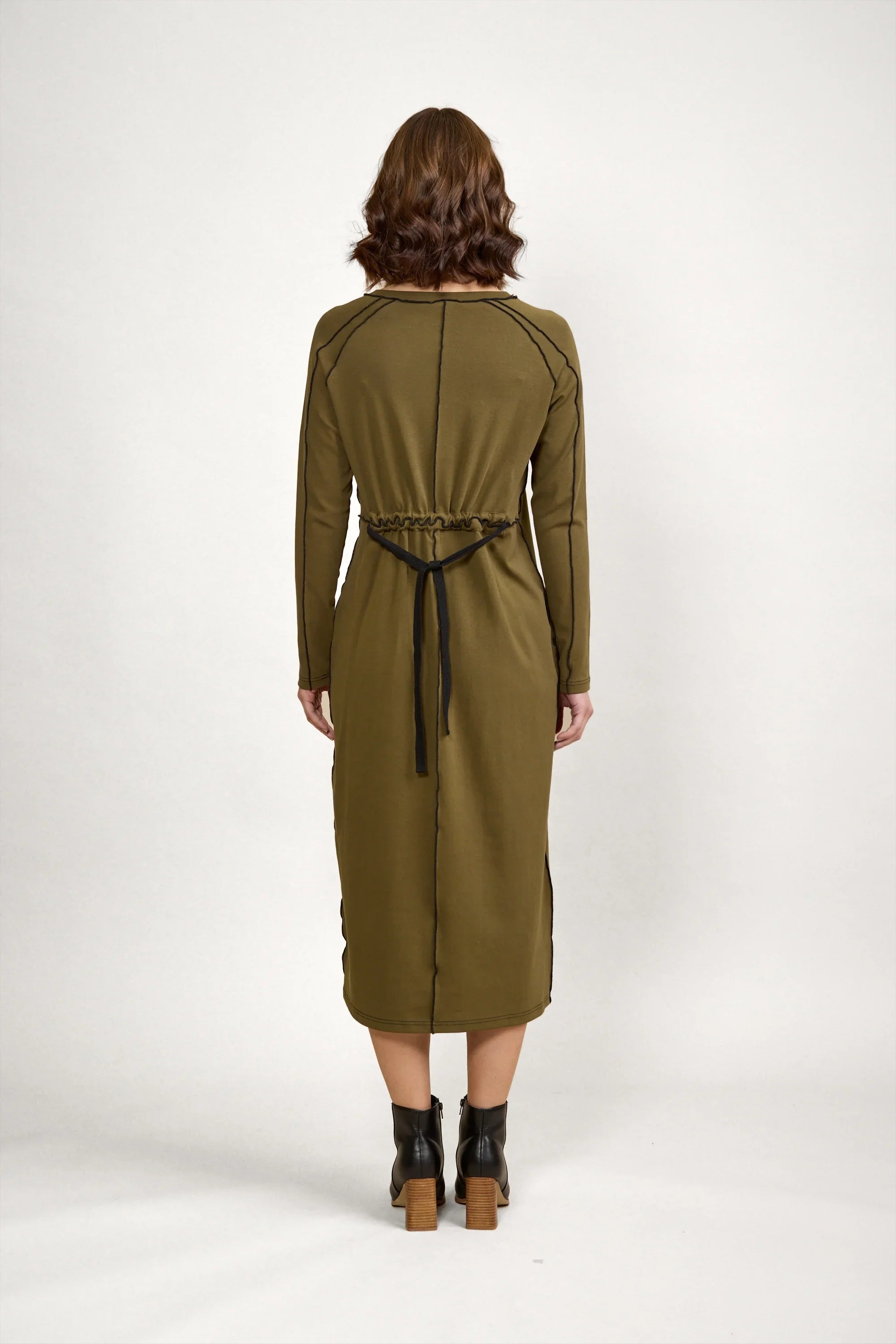 Back view of woman wearing olive green long sleeve midi dress with black tie waist