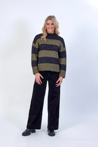 Woman wearing khaki and black striped knit sweater with black wide-leg pants and boots
