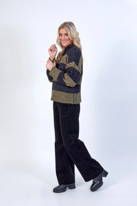 Woman wearing khaki and black striped sweater with black pants and platform shoes