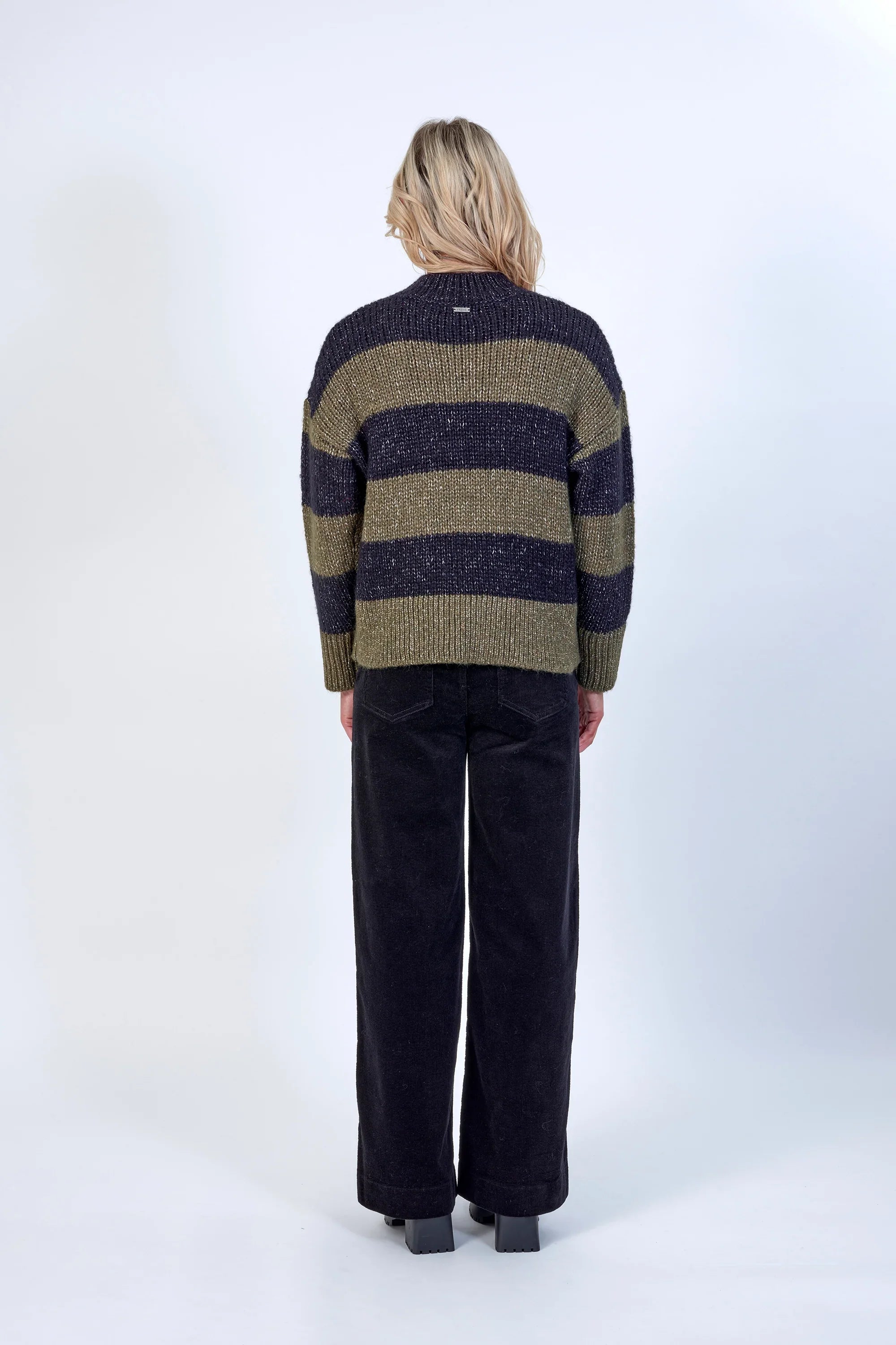 Back view of a model in a khaki and black striped knit sweater with black wide-leg pants
