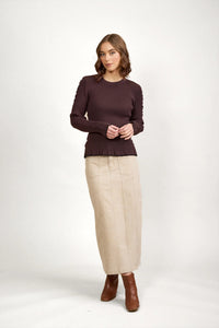 Woman wearing a chocolate brown ribbed sweater with beige maxi skirt and brown boots