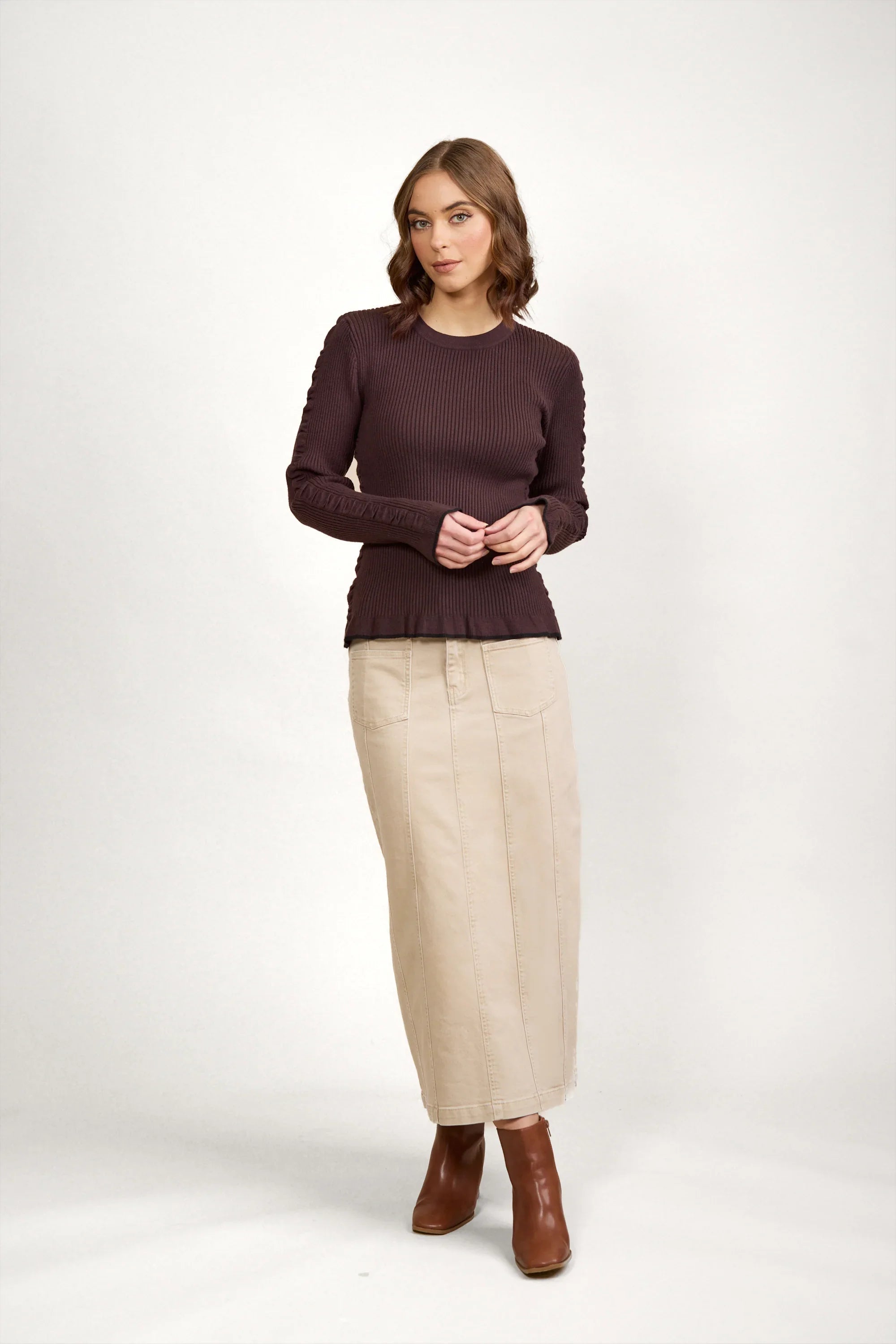Woman wearing a chocolate brown ribbed sweater with beige maxi skirt and brown boots