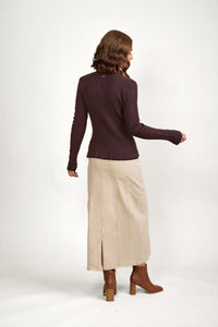 Woman wearing a chocolate ribbed knit sweater, beige maxi skirt, and brown heeled boots