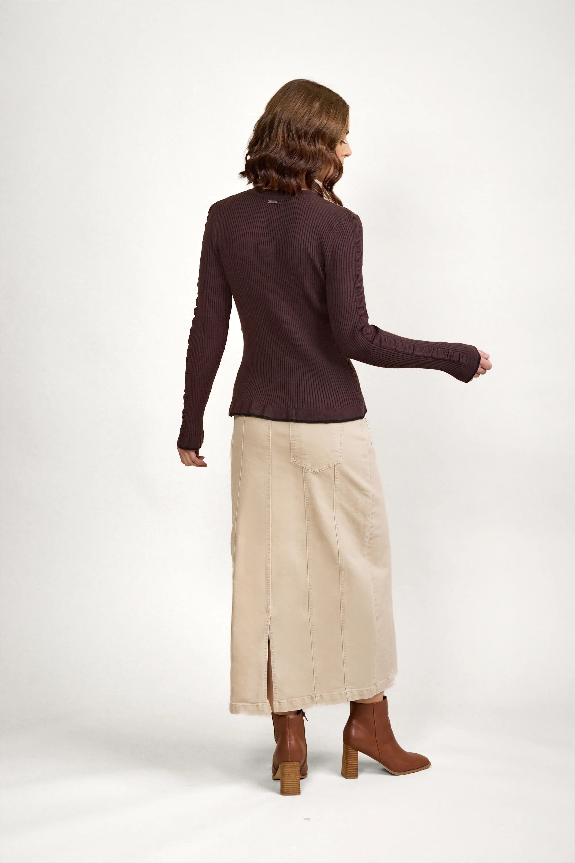Woman wearing a chocolate ribbed knit sweater, beige maxi skirt, and brown heeled boots