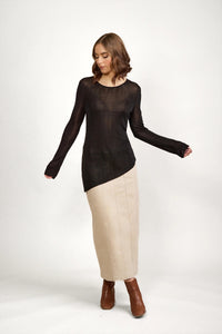 Woman wearing black sheer knit sweater, beige maxi skirt, and brown ankle boots