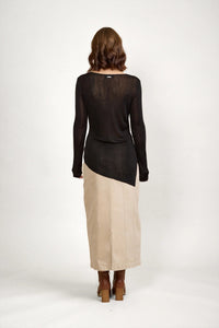 Woman wearing black long sleeve sweater and beige maxi skirt, back view, neutral background