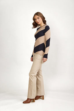 Woman wearing beige and navy striped knit sweater, beige pants, and brown heeled boots