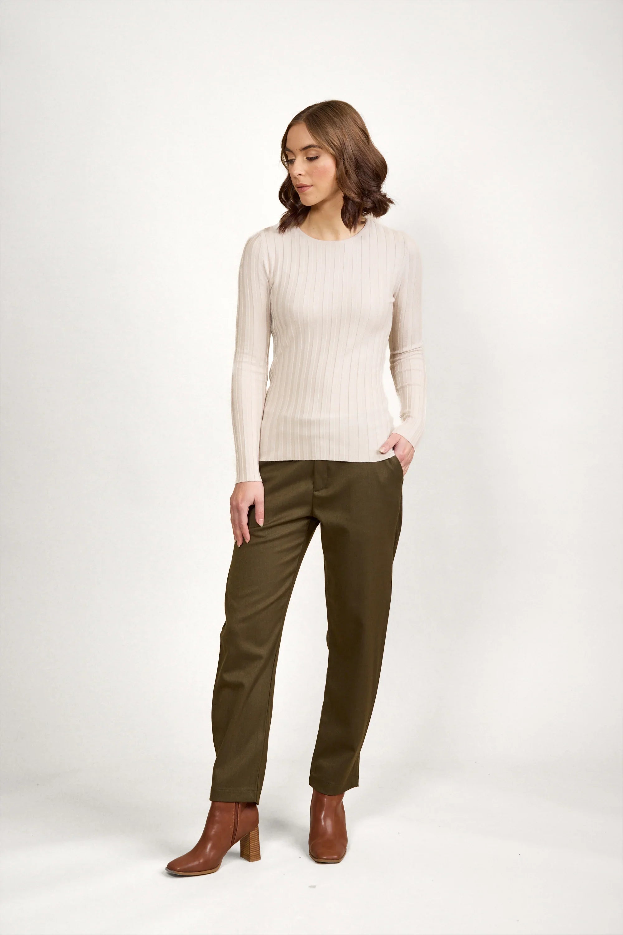 Woman wearing an oatmeal ribbed sweater with olive trousers and brown heeled boots