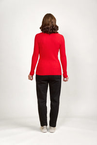 Woman wearing fitted red ribbed sweater and black pants, back view, studio background